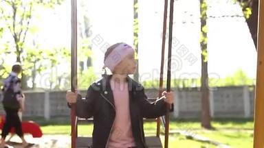 小女孩在城市公园荡秋千，快乐的孩子在荡秋千。穿粉红色衣服的概念女郎在秋千上快速挥舞。